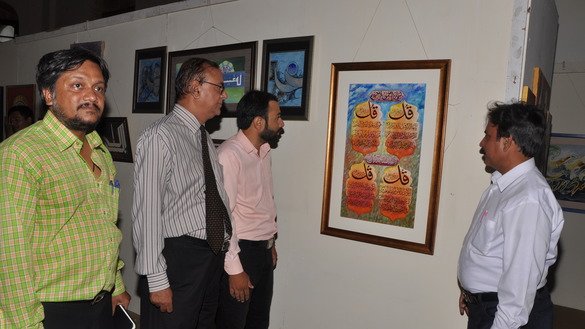Some art admirers focus on a painting at the exhibition June 19. [Javed Mahmood]