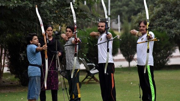 Sara Khan teaches students how to aim and shoot an arrow. [Muhammad Shakil]