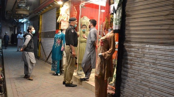 A police officer March 22 tells a shopkeeper to close his shop before 7pm in Saddar Bazaar, Peshawar, in line with the district administration's efforts to stop the spread of coronavirus. [Shahbaz Butt]