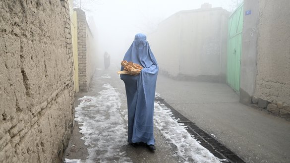 18 جنوری کو کابل میں ایک عورت ایک بیکری سے مفت روٹی لینے کے بعد اپنے گھر کی طرف جانے والی سڑک پر چلتے ہوئے۔ [وکیل کوہسار/اے ایف پی]