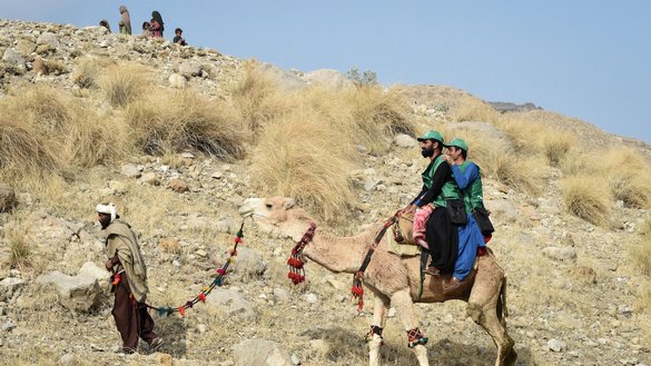 Census officials from the Pakistan Bureau of Statistics ride a camel to collect information from Marri tribespeople in Mawand, Balochistan province. [Banaras Khan/AFP]