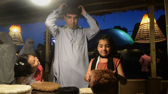 9 مئی کو پشاور ہنر میلے میں ایک لڑکی اپنے والد کو ایک اونی ٹوپی پہن کر دیکھتے ہوئے دیکھ رہی ہے۔ [شہباز بٹ]