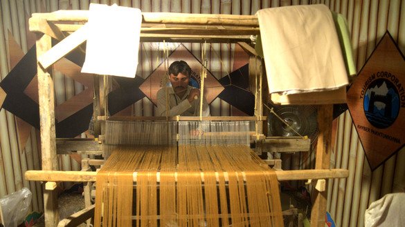 A tailor weaves clothing through a traditional loom at the Hunar Mela May 9. [Shahbaz Butt]