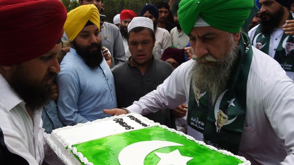 پاکستانی سکھ 14 اگست کو پشاور میں پاکستان کے یومِ آزادی کے موقع پر پاکستانی جھنڈے سے سجایا گیا کیک اٹھائے ہوئے ہیں۔ ملک نے 70 سال پہلے برطانیہ سے آزادی حاصل کی تھی۔ ]عبدل مجید/ اے ایف پی[