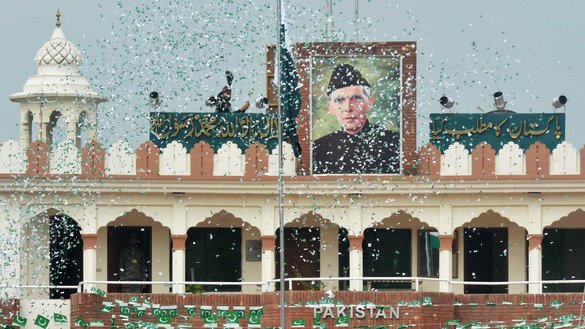 The portrait of Muhammad Ali Jinnah is seen at at the India-Pakistan Wagah border post as a Pakistani Ranger (top) unfurls the Pakistani national flag to celebrate Independence Day August 14. Jinnah was the founder of Pakistan, which gained independence from Great Britain 70 years ago. [Narinder Nanu/AFP]