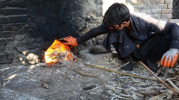A farmer in Charsadda District fuels the fire of a traditional sugarcane mill in January. [Alamgir Khan]