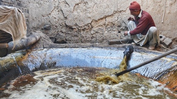 A farmer in Charsadda District in January pours sugarcane juice into a heated reservoir to make gur. [Alamgir Khan]