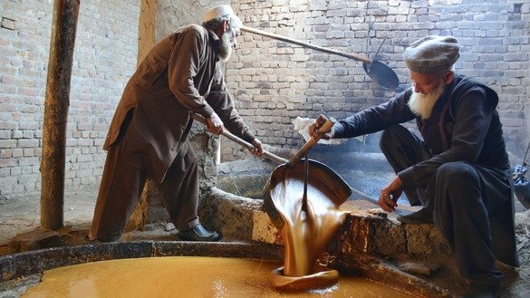 Farmers transfer liquid gur from a cooking vessel to a processing vessel in Charsadda District in January. [Alamgir Khan]