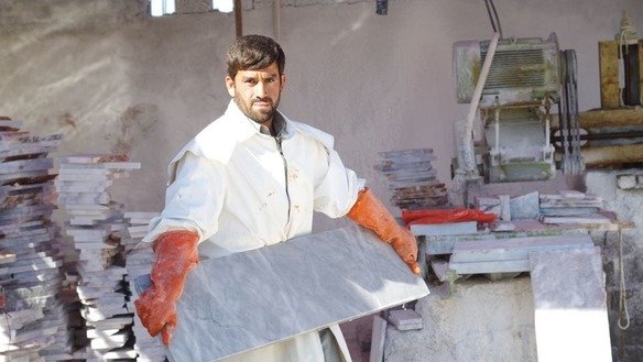 A factory worker holds a slab of processed marble in Mohmand Agency in May. [Alamgir Khan]