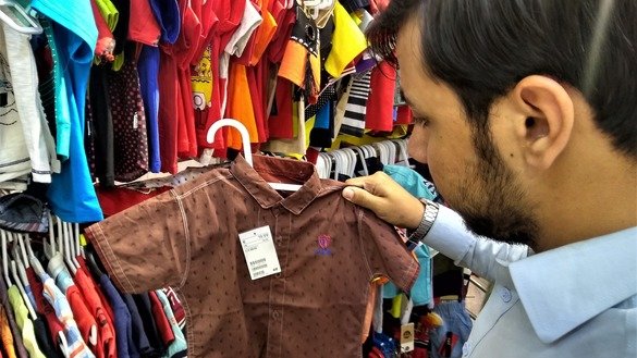 A customer in Rawalpindi buys a child's shirt June 10 for Eid ul Fitr. [Syed Abdul Basit]