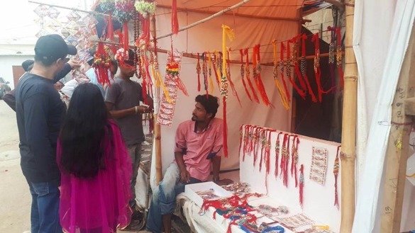 Shoppers peruse a rahki vendor's goods at the Shri Swaminarayan Mandir in Karachi August 22. [Zia Ur Rehman]
