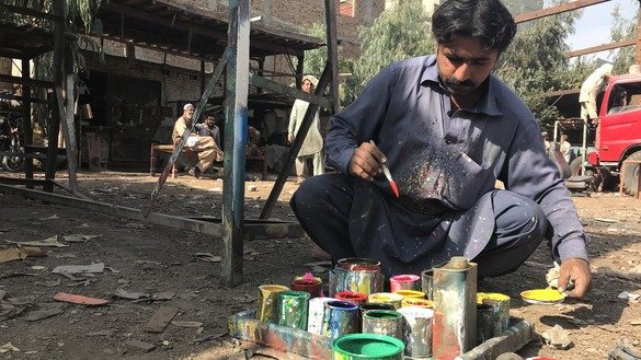 A painter in Peshawar prepares to paint a truck December 10. [Nazar ul Islam]