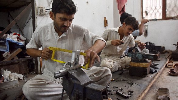 An artisan gunsmith puts the finishing touches on a locally made pistol in Peshawar last November 15. [Adeel Saeed]