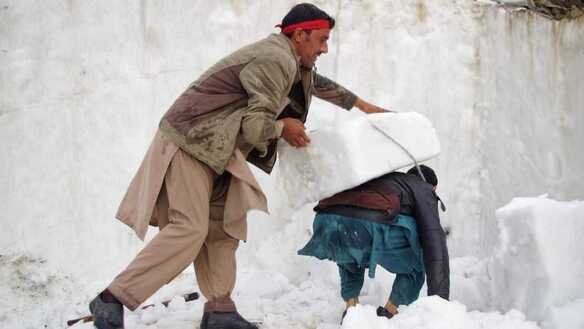 چترال کا ایک رہائشی یکم جولائی کو برف کا ٹکڑا لے جانے میں دوسرے شہری کی مدد کر رہا ہے۔ [عالمگیر خان]