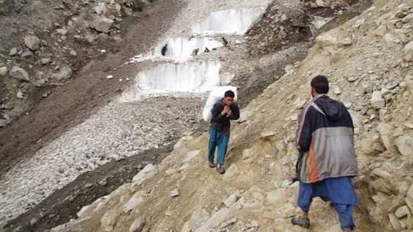 A Chitral resident carries glacier ice on his back on July 1. [Alamgir Khan]