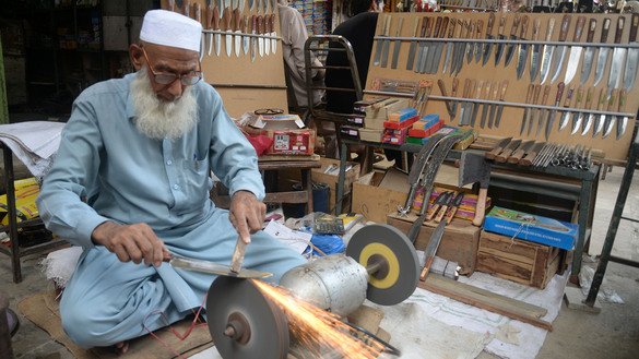 A blacksmith in Peshawar sharpens knives ahead of Eid ul Adha on Jul 31. [Shahbaz Butt]