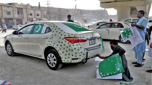 Workers in Peshawar decorate a car in preparation for Independence Day. [Shahbaz Butt]