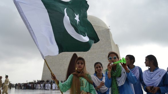 کراچی میں 14 اگست کو یومِ آزادی کے موقع پر ہونے والی تقریبات میں پاکستانی لڑکیاں، بانیِ پاکستان قائد اعظم محمد علی جناح کے مزار کے آگے قومی جھنڈا اٹھائے کھڑی ہیں۔ [رضوان تبسم/ اے ایف پی]