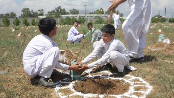 18 اگست کو ’پلانٹ فار پاکستان‘ مہم کے دوران ضلع باجوڑ میں سکول کے بچے ایک پودا لگا رہے ہیں۔ [حنیف اللہ]