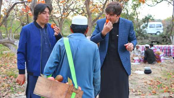 Customers in Mohmand District eat persimmons December 3. [Alamgir Khan]