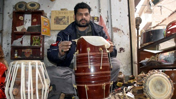 ایک کاریگر، احمد علی، 20 دسمبر کو پشاور میں اپنی دکان میں ایک دف کی مرمت کرنے میں مصروف۔ [عدیل سعید]