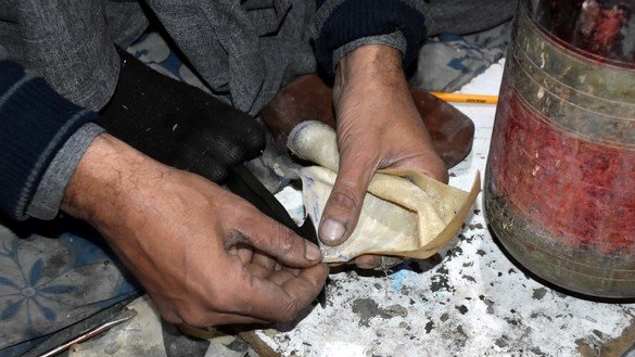 An artisan in Peshawar puts an animal hide over a drum on December 20. [Adeel Saeed]