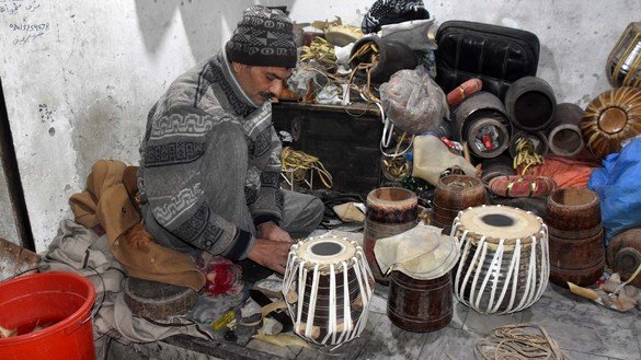 An artisan in Peshawar fixes musical instruments on December 20. [Adeel Saeed]
