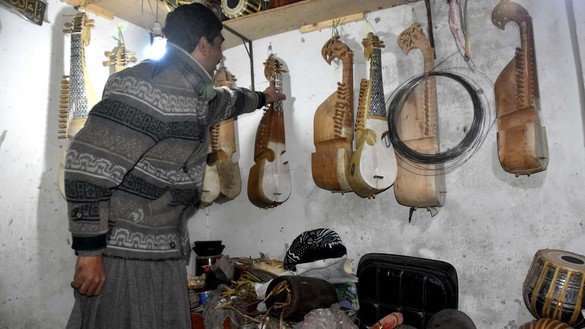 پشاور میں آلاتِ موسیقی کی ایک دکان کا مالک 20 دسمبر کو ایک گاہک کو رباب دکھاتے ہوئے۔ [عدیل سعید]