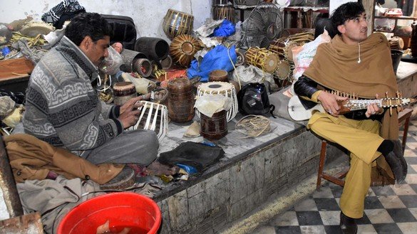A customer at a music shop in Peshawar plays a rabab on December 20. [Adeel Saeed]