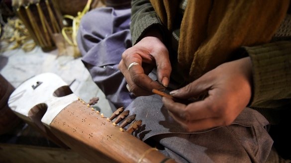 3 دسمبر کو لی گئی اس تصویر میں پشاور کے نواح میں ایک کارخانے میں ایک کارکن روائتی آلہٴ موسیقی رباب بنا رہا ہے۔ [عبدالمجید /اے ایف پی]