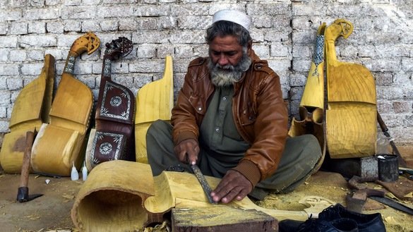 10 دسمبر کو لی گئی اس تصویر میں ایک کارکن پشاور کے نواح میں ایک کارخانہ میں روایتی آلہٴ موسیقی رباب تیار کر رہا ہے۔ [عبدالمجید /اے ایف پی]