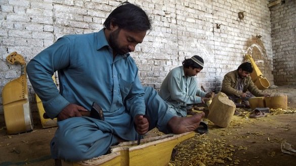 10 دسمبر کو لی گئی اس تصویر میں کارکنان پشاور کے نواح میں ایک کارخانہ میں روایتی آلاتِ موسیقی رباب تیار کر رہے ہیں۔ [عبدالمجید /اے ایف پی]