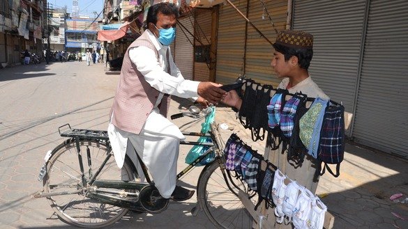 A man buys face masks from a street vendor in front of a closed market in Peshawar March 22. [Shahbaz Butt]