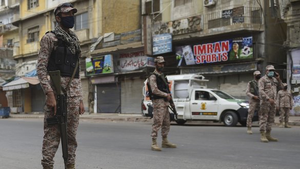 Pakistani soldiers wearing face masks stand guard on a deserted street in Karachi on March 23 amid a lockdown. [Rizwan Tabassum/AFP]