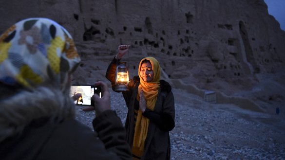 A woman poses for a picture near the empty alcove where the Shahmama Buddha -- the smaller of the two statues -- once stood during a March 9 ceremony marking the 20th anniversary of its destruction by the Taliban. [Wakil Kohshar/AFP]
