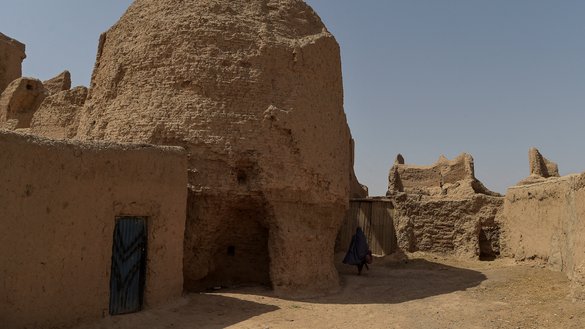 An internally displaced Afghan woman walks toward her home at the historic site of Qala-e-Kohna in Lashkargah, Helmand province, on March 27. [Wakil Kohsar/AFP]