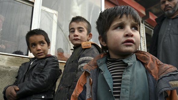Children wait to receive free bread from a bakery in Kabul on January 18. [Wakil Kohsar/AFP]