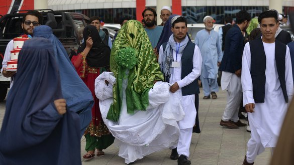 کابل میں 13 جون کو، اجتماعی شادی کی تقریب کے بعد ایک افغان جوڑا شادی ہال کے باہر چہل قدمی کر رہا ہے۔ [سہیل ارمان/اے ایف پی]