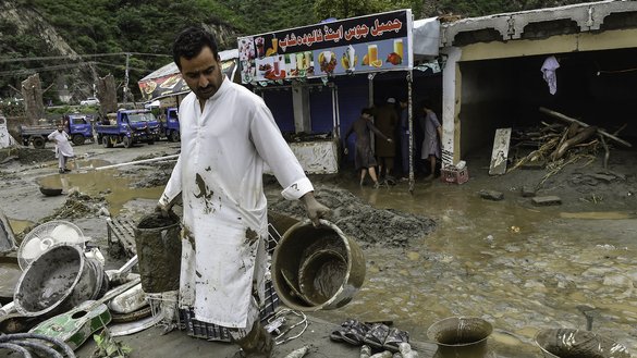 Shopkeepers after heavy monsoon rains collect their belongings from the mud outside their damaged shops in Mingora, Swat Valley, on August 27. [Abdul Majeed/AFP]