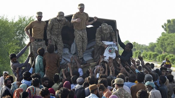 Pakistani army soldiers distribute relief food bags to flood survivors in Shikarpur of Sindh province on August 28. [Asif Hassan/AFP]